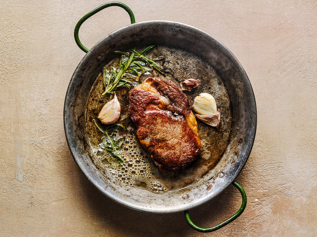 ribeye steak served with garlic rosemary and butter (cooked dish)